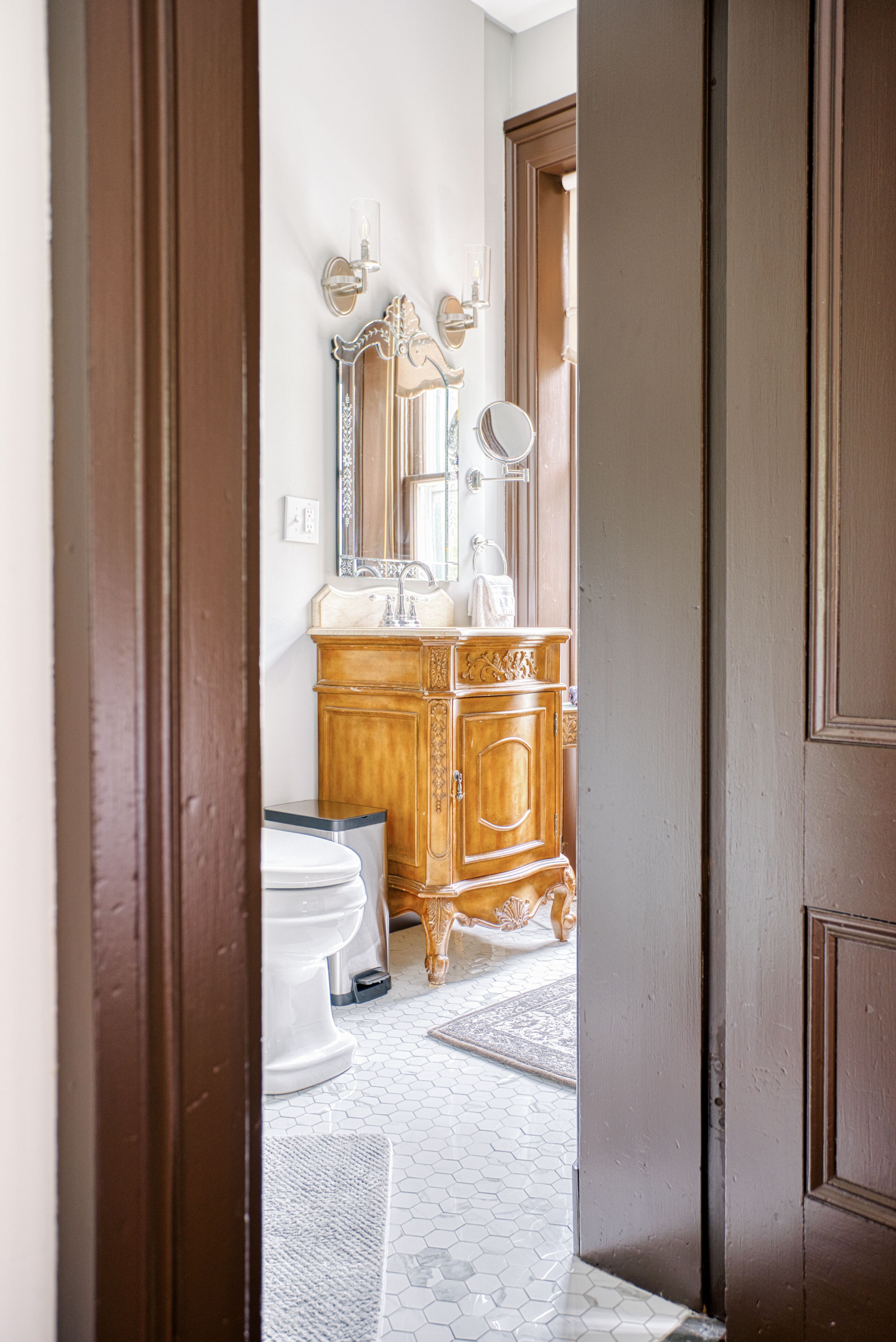 A bathroom with a wooden vanity, a mirror, and a toilet.