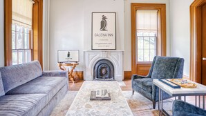 Una sala de estar con chimenea, un sofá, una silla y una mesa con un juego de mesa.