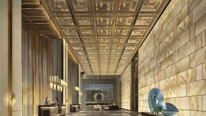 Un hall d’entrée spacieux, doté d’un plafond haut, de murs en marbre et d’une sculpture centrale.