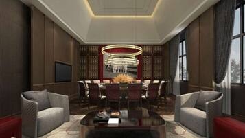 A modern living room with a central dining area, a large chandelier, and a TV mounted on the wall.