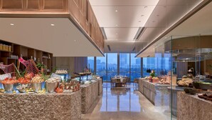 Un hall d’hôtel moderne, doté d’un plafond haut, d’un sol en marbre et d’un îlot central où sont présentés des produits de la mer.
