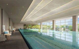 Uma piscina interior ampla, com design alongado, rodeada por áreas de estar e grandes janelas que oferecem vista para o exterior.