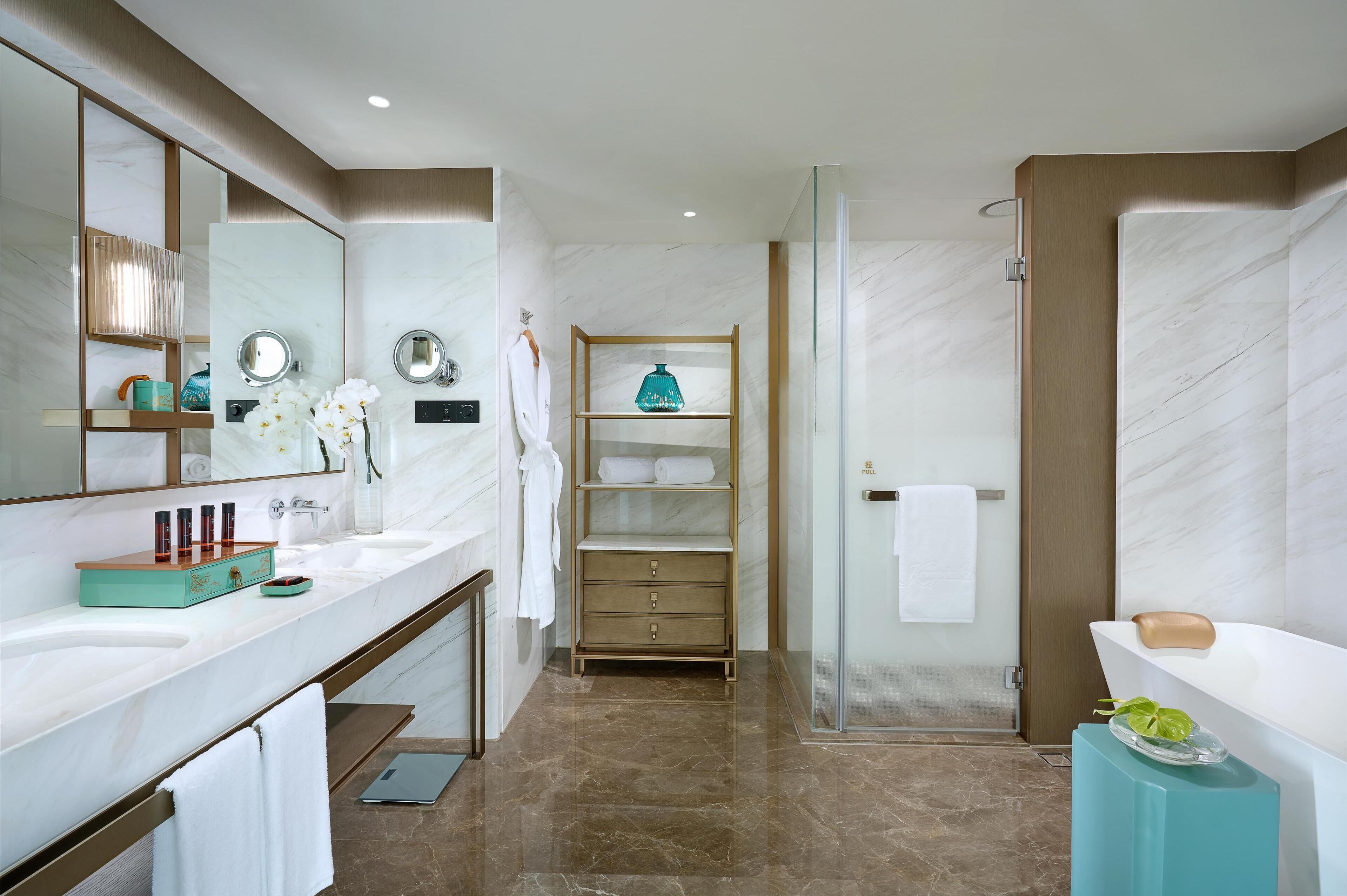 Een moderne badkamer met een grote spiegel, twee wastafels, een douche en een wastafelmeubel met een plank.