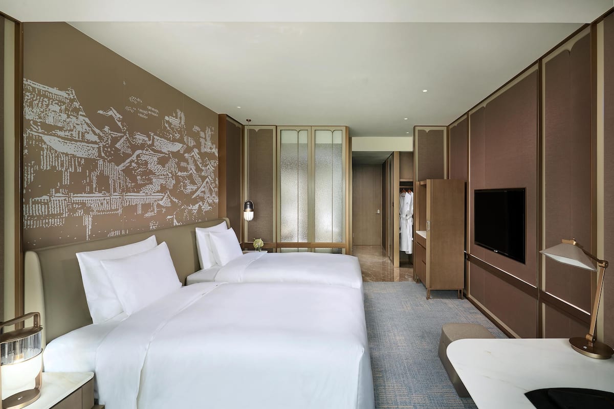 Une chambre d’hôtel avec un grand lit, une télévision et une armoire.