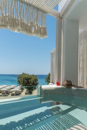 A poolside view with a clear blue sky, a beach, and a tree. - Virtu Suites (Naxos)