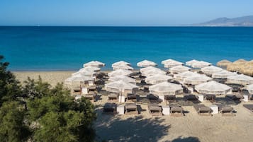 Aan het strand, wit zand, ligstoelen aan het strand, parasols