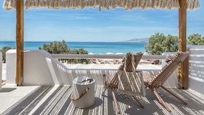 A balcony with a view of the sea, a wooden chair, a white bucket, and a rope. - Virtu Suites (Naxos)