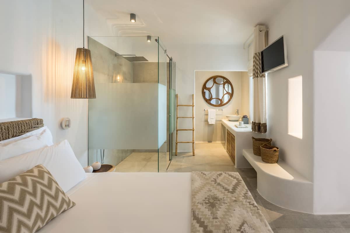 Une chambre d’hôtel moderne équipée d’un lit, d’une douche, d’une salle de bain et d’un téléviseur fixé au mur.