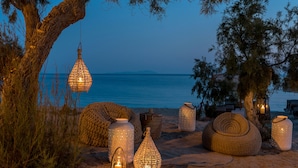 A beach setting with various decorative lanterns and woven seating arrangements. - Virtu Suites (Naxos)