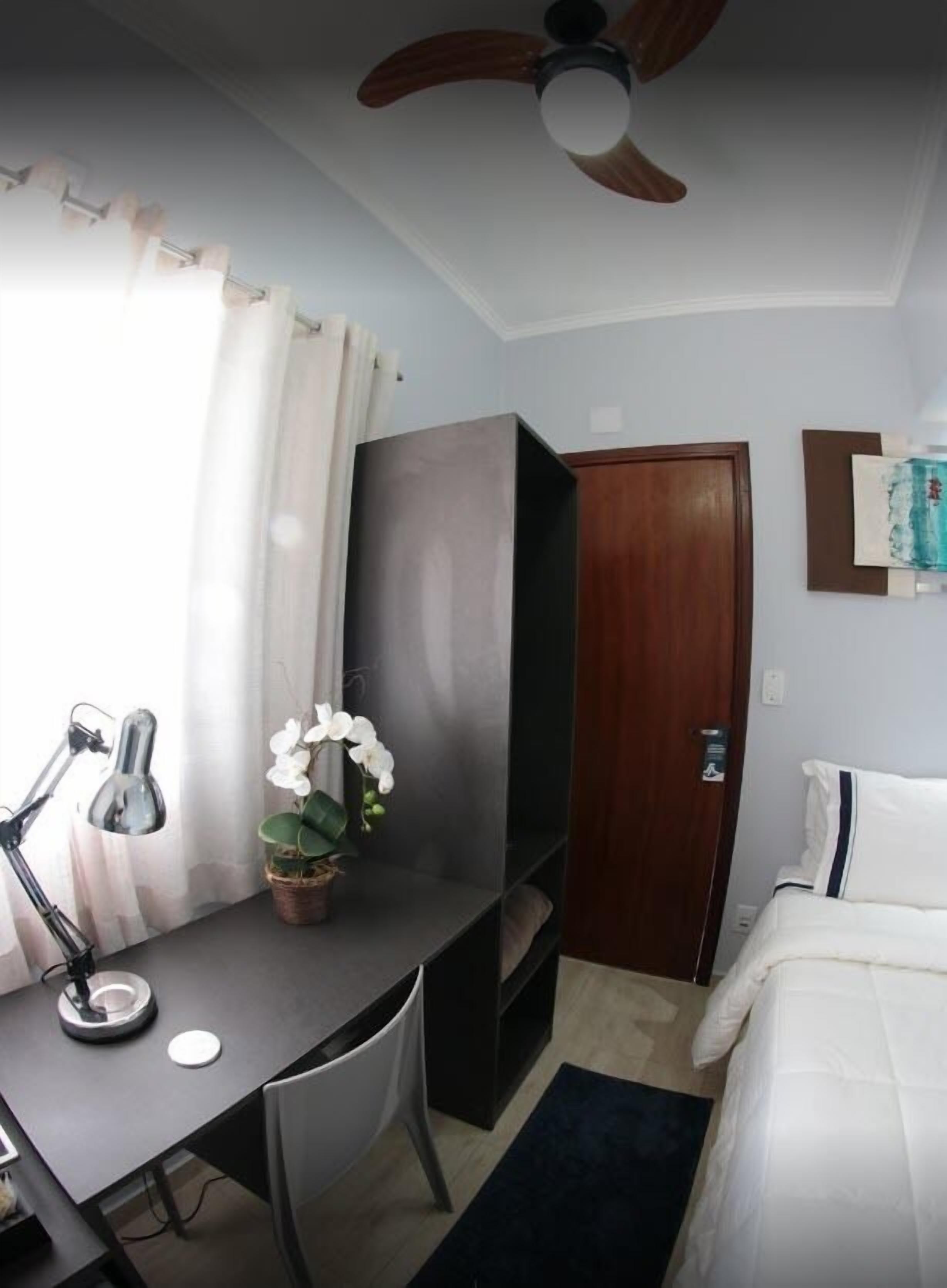 Una habitación de hotel compacta con escritorio, silla y cama.