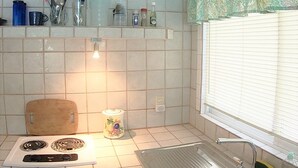 Uma cozinha compacta com fogão, pia e janela com persianas.