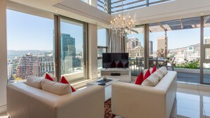 A modern living room with a large TV, white sofas, and a chandelier. - Mirage - WHosting (Cape Town)