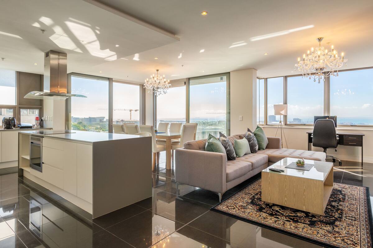 A modern living room with a sofa, coffee table, and a view of the city through large windows.