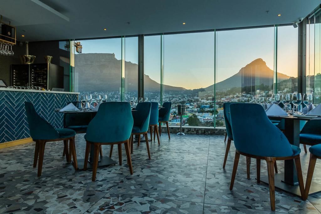 A restaurant with a terrace overlooking a cityscape and a mountain. - Mirage - WHosting (Cape Town)