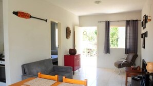 Una sala de estar moderna con un sofá, una mesa de comedor con manteles individuales, un aparador rojo y vistas al exterior.