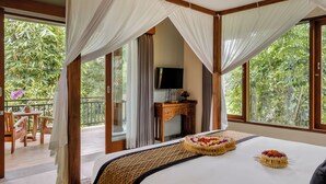 A bedroom with a large bed, a TV, and a balcony with a table and chairs. - Kubu Rama Ubud Cottage (Ubud)