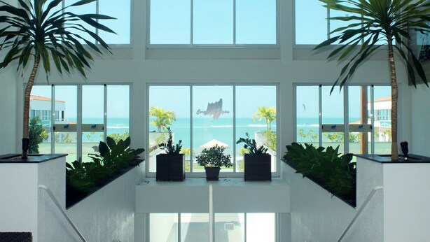 Un intérieur spacieux avec de grandes fenêtres donnant sur l’océan et un bâtiment sur lequel on peut lire l’inscription « Coral Springs ».