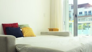 Une chambre d’hôtel avec un lit, une petite table et une vue sur un immeuble par la fenêtre.