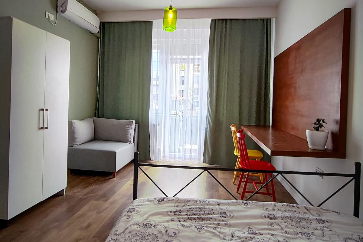 A modern bedroom with a bed, a desk, and a sofa.