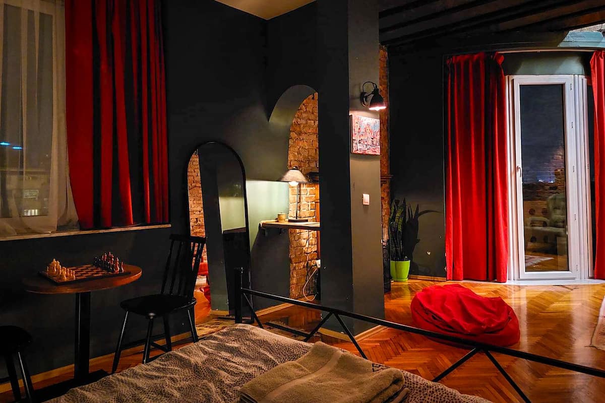 A cozy living room with a chessboard, a red bean bag, and a dining area with a table and chairs.