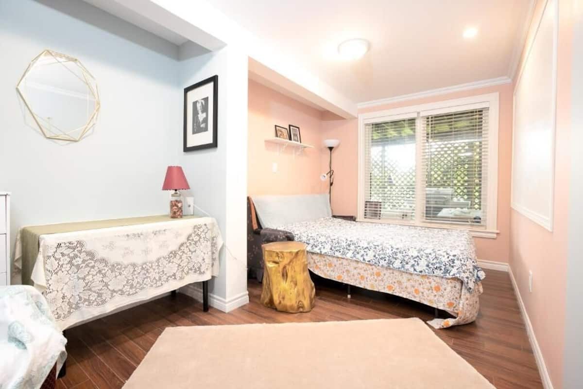 A bedroom with a bed, bedside table, lamp, and window.