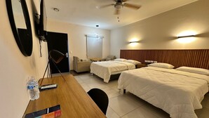 Hotelkamer met twee bedden, een bureau met stoel, plafondventilator, televisie en spiegel.