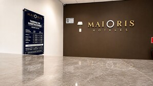Een hotel receptie met een bord waarop de kamerprijzen staan vermeld en een muur met de naam van het hotel.
