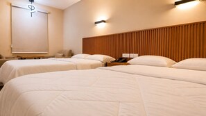 Camera d'albergo con due letti, una testiera in legno, un comodino con un telefono e un lampadario a parete.