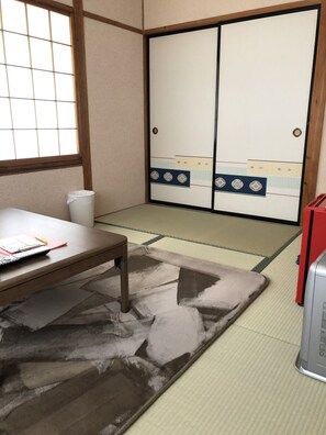 A traditional Japanese room with tatami flooring, a low wooden table, a red cabinet, and sliding shoji doors. - Oyado Zen (Kusatsu)