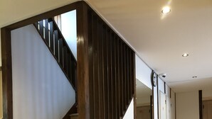 Una escalera con barandillas de madera y piso cubierto de alfombra color beige.