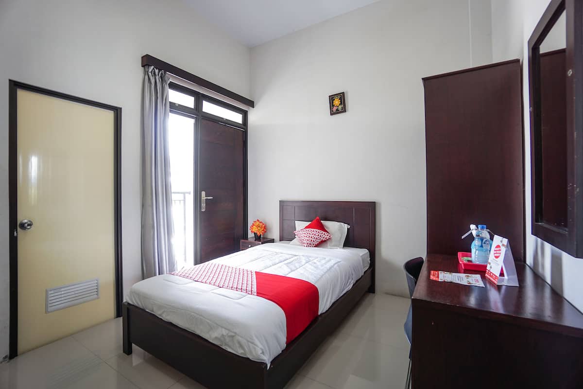 Quarto de hotel bem arrumado, com cama, cómoda, espelho e porta.