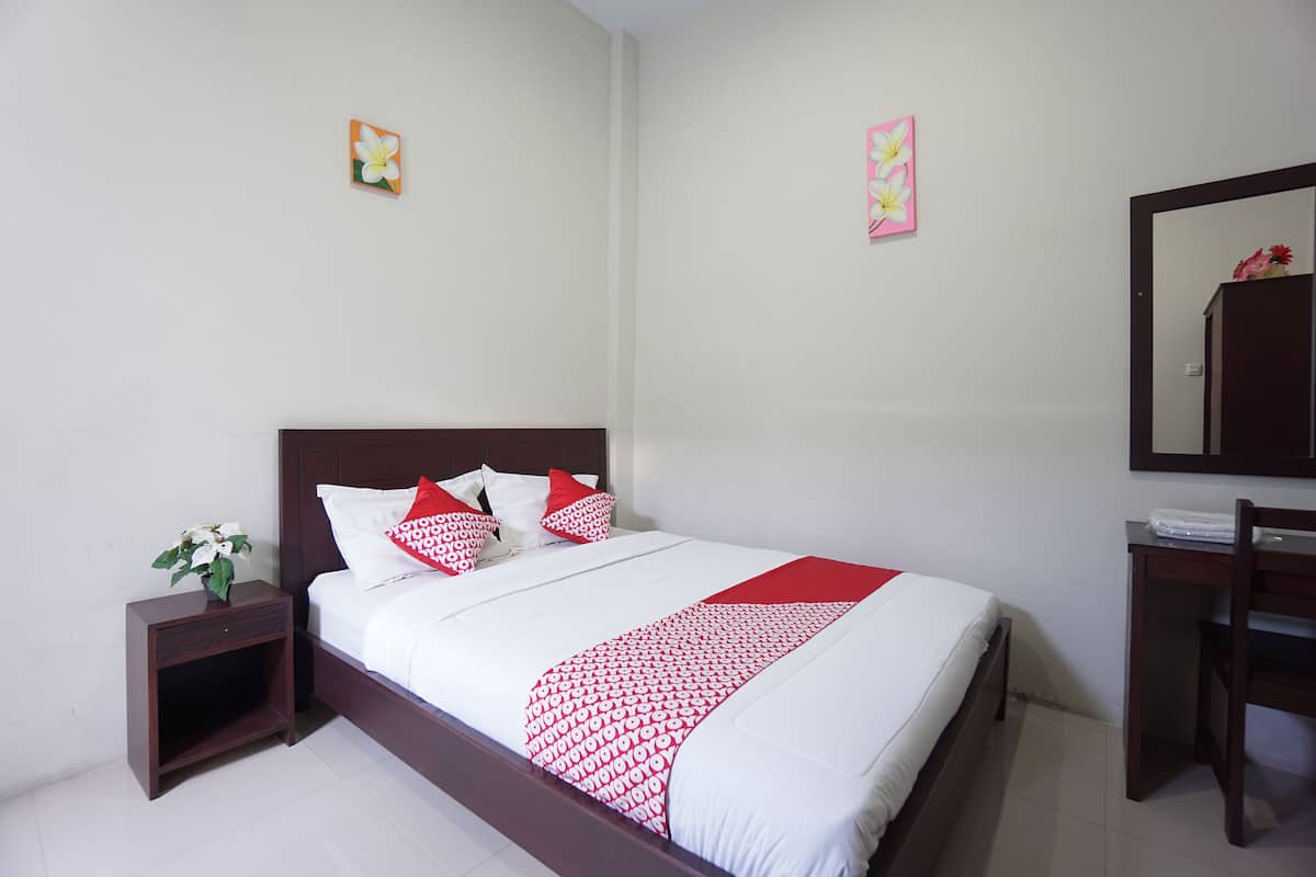 Quarto bem arrumado com cama, mesa de cabeceira e escrivaninha com cadeira.