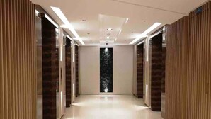 A modern hallway with a glossy floor, wooden paneling on the walls, and recessed lighting.