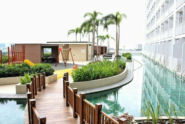Relax by the pool surrounded by lush greenery and palm trees.
