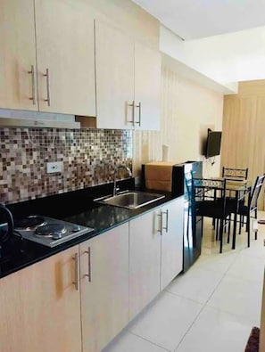 Enjoy meals in this well-equipped kitchen with a stainless steel sink, black countertop, and mosaic backsplash.