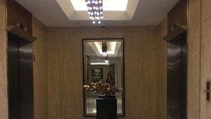A modern elevator lobby with a reflective floor, a central decorative piece, and two elevators. - Breeze Residences by Ridged (Pasay)