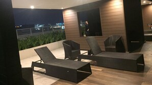An outdoor seating area with two lounge chairs and a table, overlooking a cityscape at night. - Breeze Residences by Ridged (Pasay)
