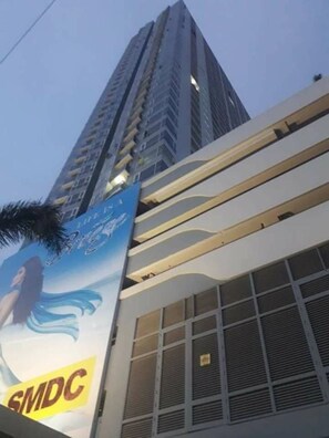 Un edificio alto con un diseño moderno, que destaca un cartel prominente de 'SMDC' en la fachada.