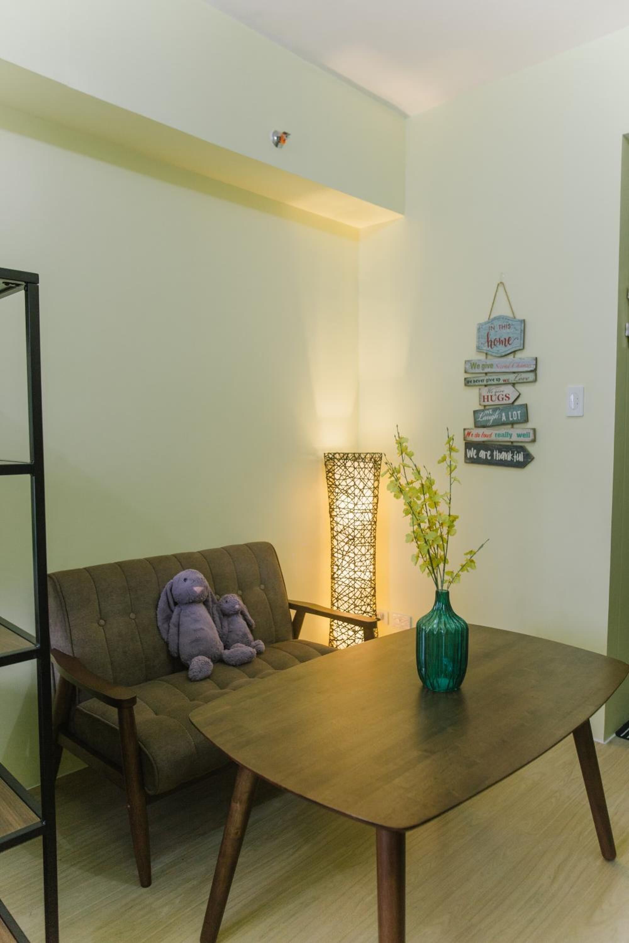 A room with a sofa, a table, a green vase, and wall decorations.