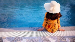 A person sitting by a pool with a tiled edge. - Kim Bao Hotel (Hai Phong)