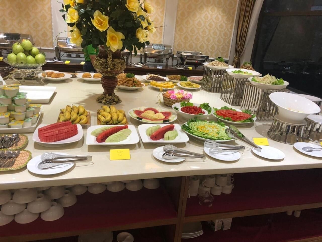 A buffet table with various food items and utensils.