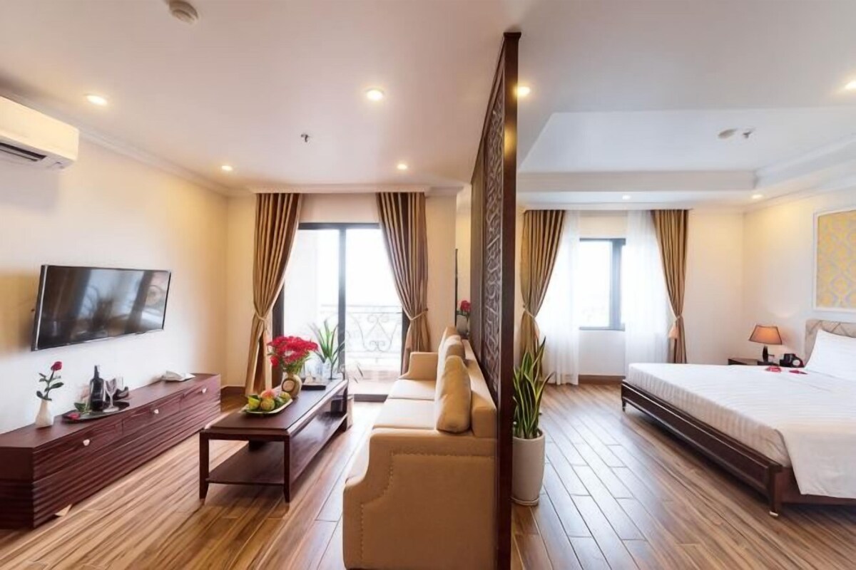 A hotel room with a bed, a sofa, a TV, a desk, and a balcony.