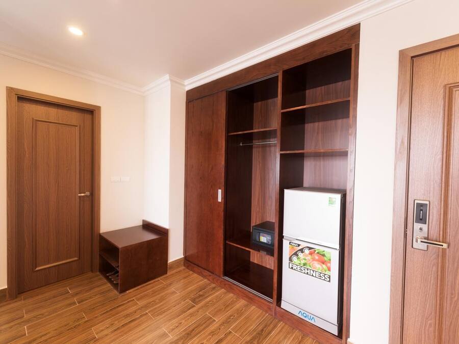 Una habitación con un armario de madera, un pequeño banco y un refrigerador con una etiqueta de productos frescos.