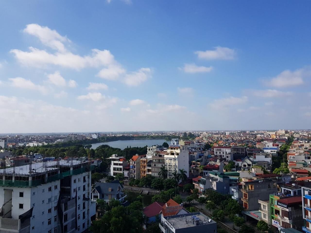A cityscape with a mix of residential and commercial buildings, a body of water in the distance, and a clear sky.