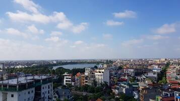 A cityscape with a mix of residential and commercial buildings, a body of water in the distance, and a clear sky.