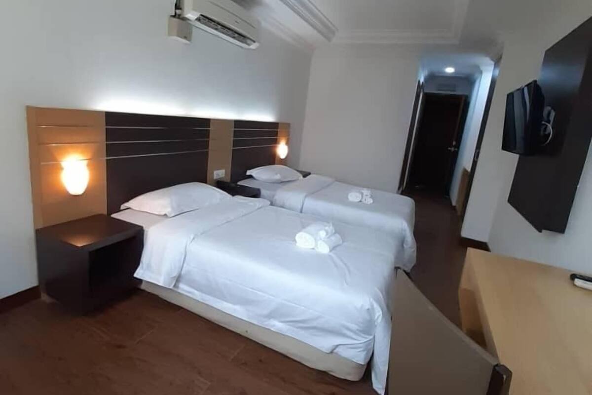 Habitación de hotel con dos camas, un escritorio, una silla, un televisor y un aire acondicionado.