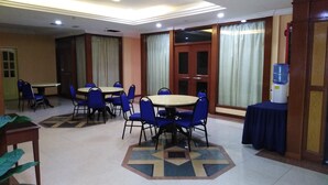 A conference room with a geometric patterned floor, blue chairs, and tables. - Sara Hotel (Labuan)