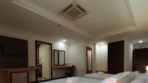 A hotel room with two beds, a desk, a TV, and a mirror. - Sara Hotel (Labuan)