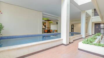 Ein Hallenbad mit Sitzgelegenheit, einer Treppe und einem Balkon.