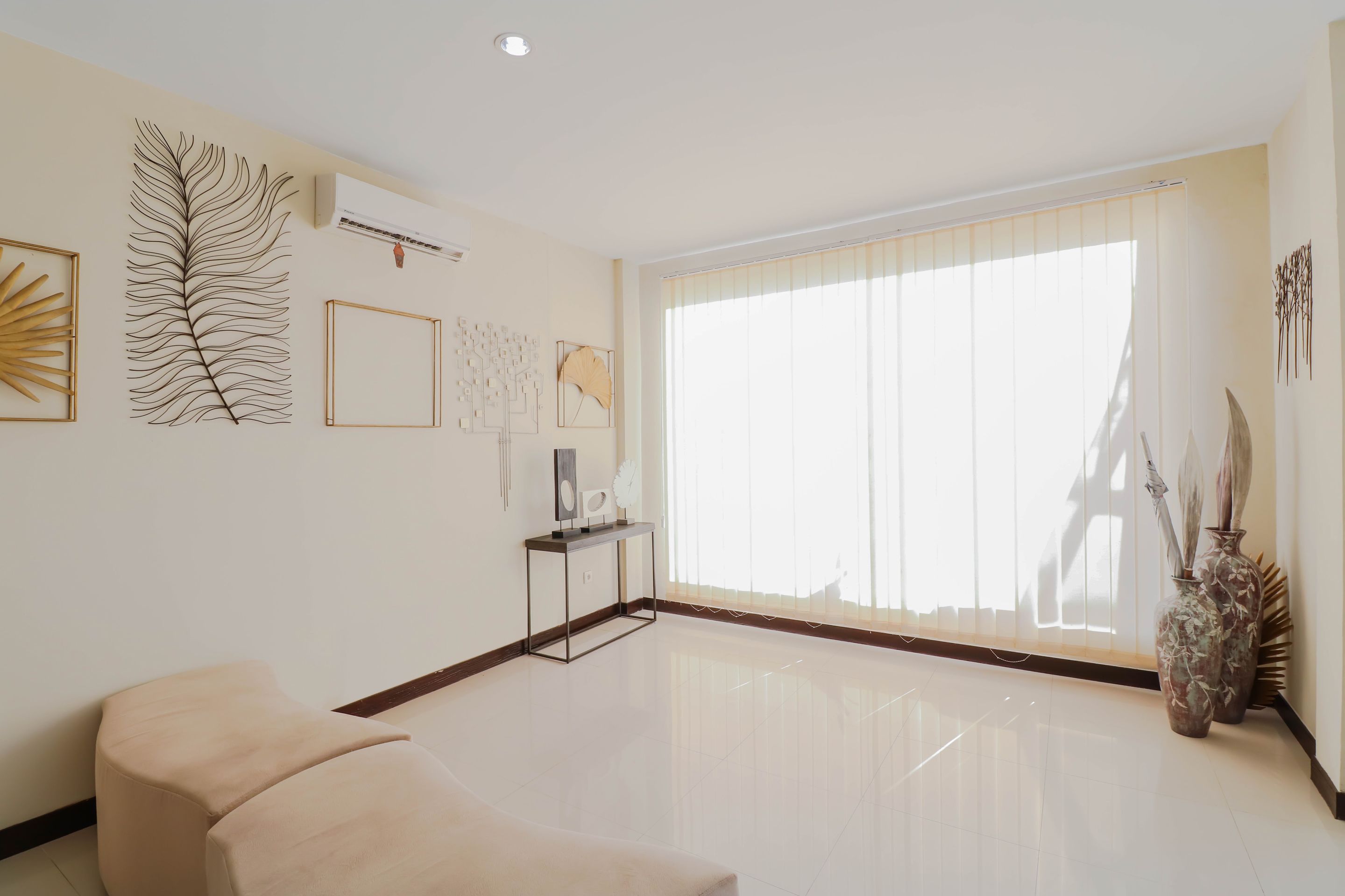 A spacious living room with a large window, a sofa, and wall art.